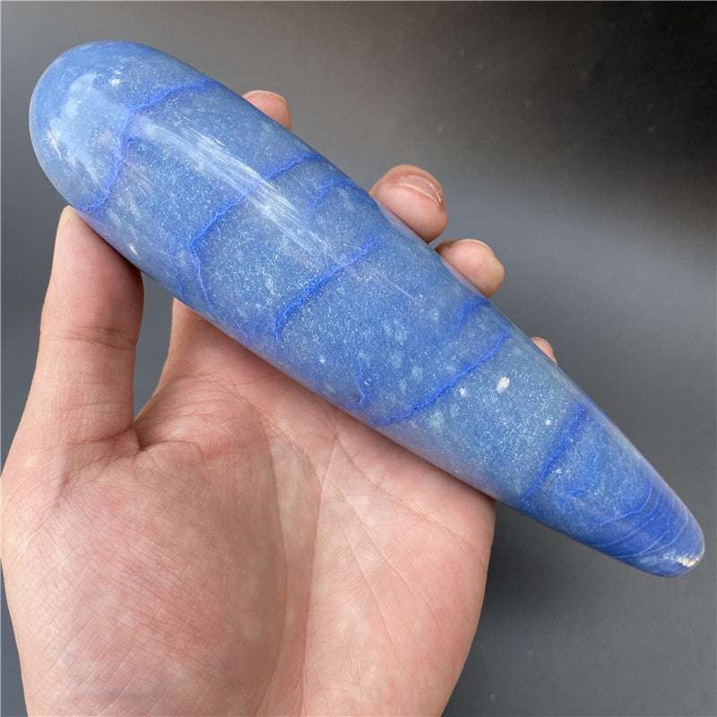 Hand holding polished blue natural stone massage stick with carved geometric design
