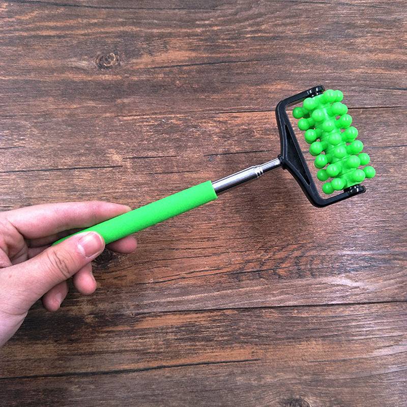 Telescopic plastic massage roller back scratcher with green handle and massage nodes on wooden background
