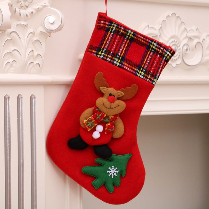 Red Christmas stocking with reindeer and Christmas tree decorations hanging on fireplace mantel Christmas decorations