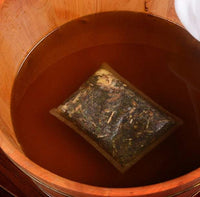 Herbal foot bath foot bag soaking in wooden basin of warm water for foot bathing therapy