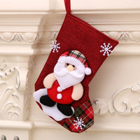 Red Christmas gift bag with Santa Claus and snowflake decorations hanging on mantel