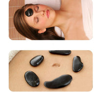 Black spa energy stones placed on face and abdomen for hot stone massage therapy
