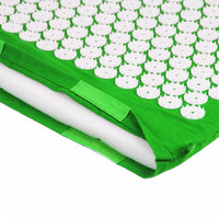 Green acupuncture massage yoga mat with white acupressure spikes and a pillow for pain relief and muscle relaxation