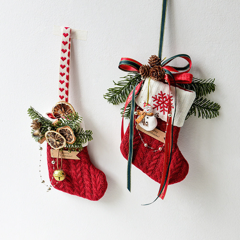 Red knitted Christmas stockings decorateFestive knitted stockings Christmas Decoration hanging by fireplaced with pine branches, dried orange slices, bells, and ribbons hanging on wall Christmas decoration