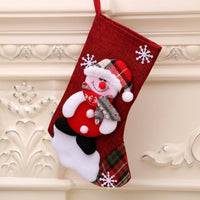 Red Christmas gift bag sock with snowman and snowflake decorations hanging on fireplace mantel