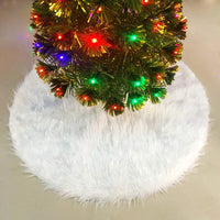 White fluffy Christmas tree skirt under decorated tree with colorful lights