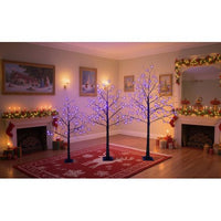 Three lighted black Halloween spooky trees with purple LED lights in various heights in a decorated living room