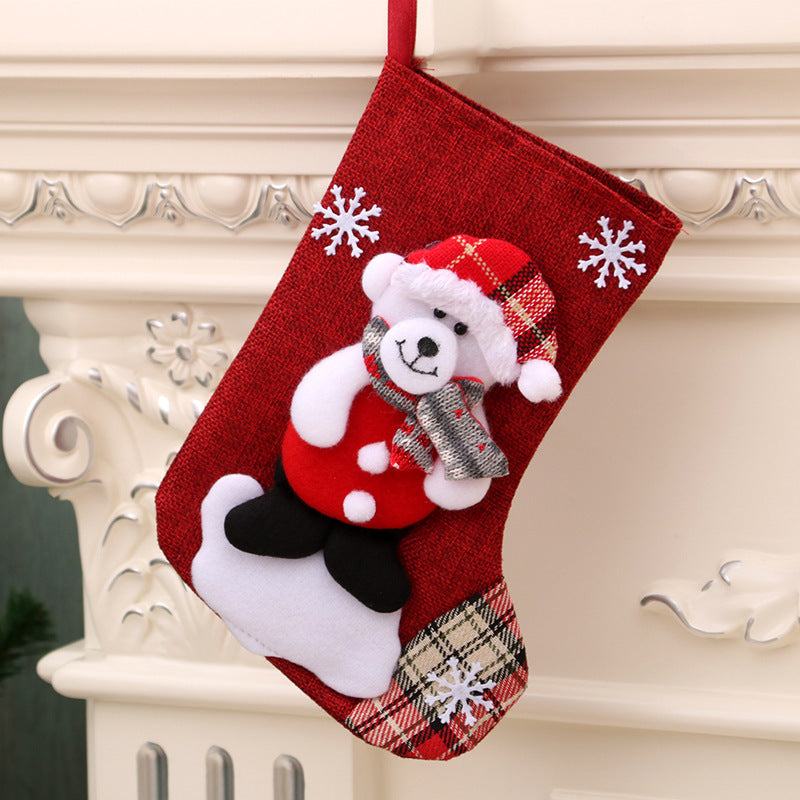 Red Christmas gift bag hanging stocking with teddy bear, snowflakes, and plaid accents