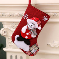 Red Christmas gift bag hanging stocking with teddy bear, snowflakes, and plaid accents