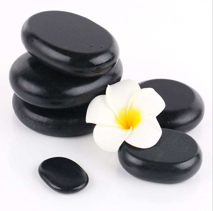 Black natural volcanic spa energy stones with white flower for hot stone massage therapy
