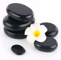 Black natural volcanic spa energy stones with white flower for hot stone massage therapy