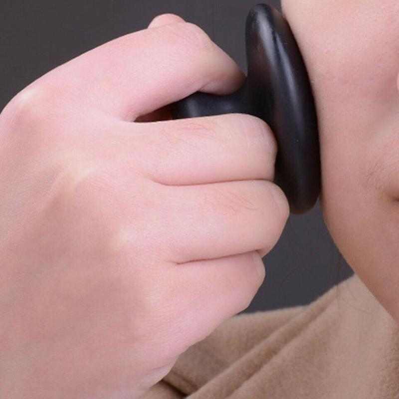 Close-up of hand using black Bianstone mushroom head massage stone on face for relaxation and massage therapy