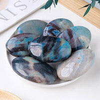 Natural crystal hot compress oval stones in blue and gray tones on a white plate