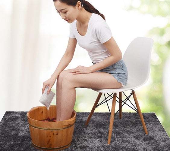 woman using foot bath foot bag with wooden basin on carpet