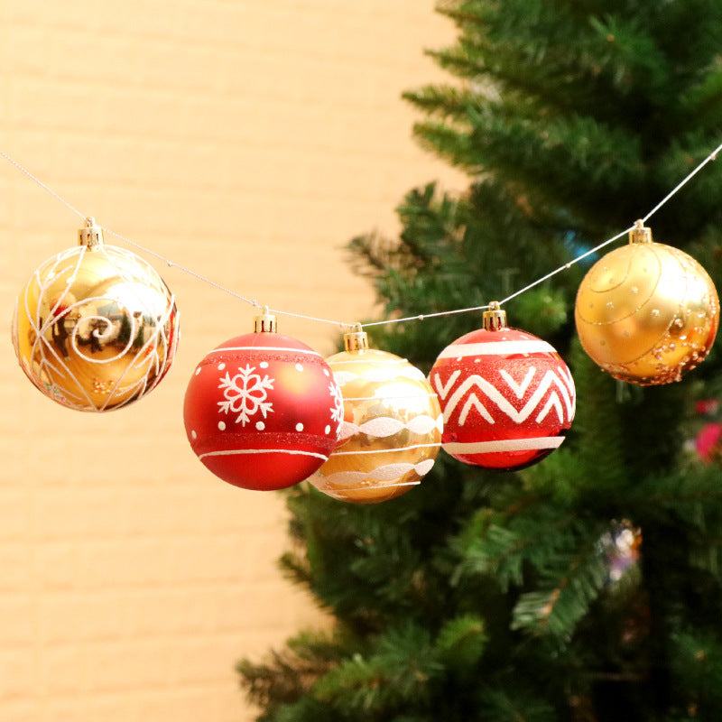 Set of hand-painted Christmas balls in red, gold, and white colors hanging on a string with a Christmas tree background
