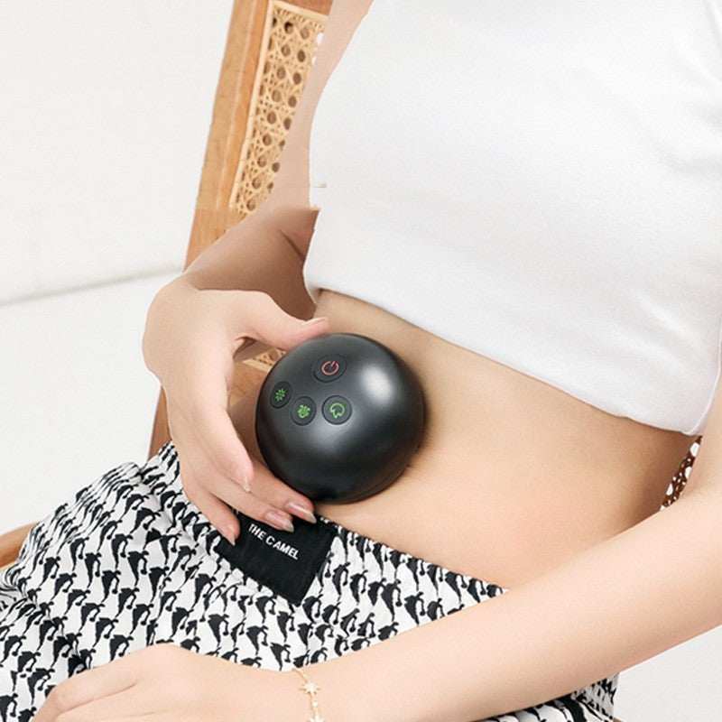 Electric Stone Gua Sha scraping massager in black used on abdomen