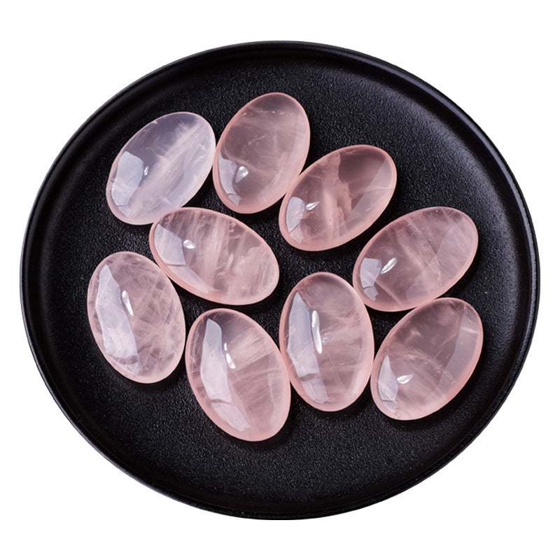 Oval natural crystal hot compress stones on a black plate