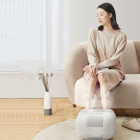 Woman using household automatic heating foot wash basin in living room for foot therapy