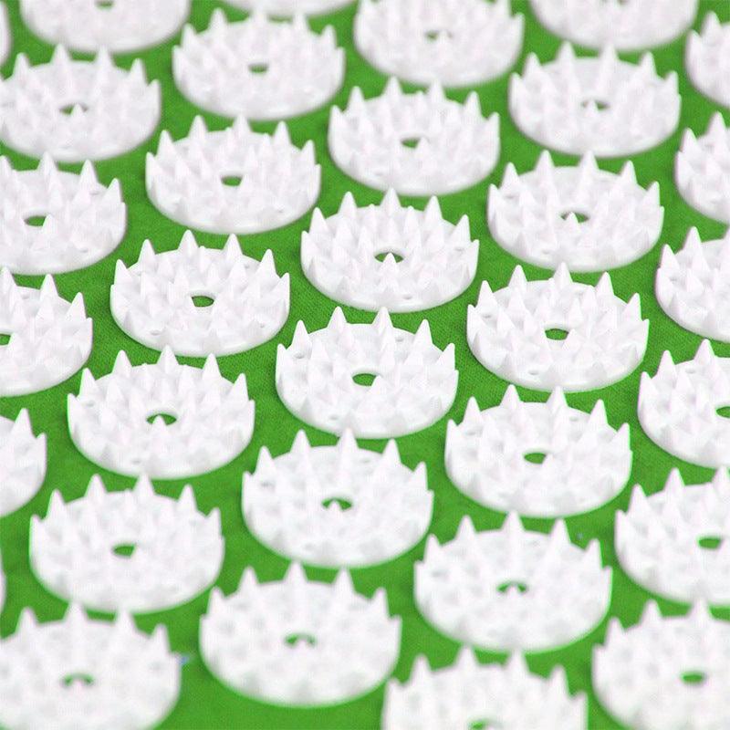 Close-up of white acupressure spikes on green acupuncture massage mat for pain relief and relaxation