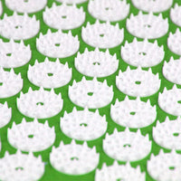 Close-up of white acupressure spikes on green acupuncture massage mat for pain relief and relaxation