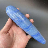Hand holding polished blue natural stone massage stick with abstract modern design