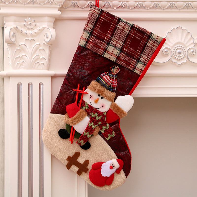 Plaid Christmas stocking with snowman and Santa Claus decoration hanging on a white fireplace mantel Christmas decorations