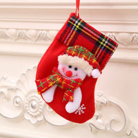 Red Christmas stocking decoration with snowman and plaid cuff hanging on white ornate wall Christmas Decorations