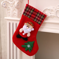 Red Christmas stocking with Santa Claus and green Christmas tree decoration hanging on white mantelpiece Christmas decorations
