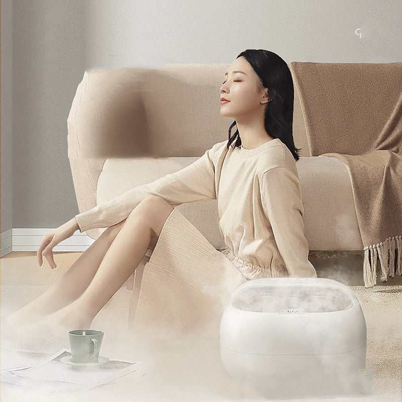 Woman relaxing with household automatic heating foot wash basin steaming in living room