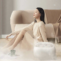 Woman relaxing with household automatic heating foot wash basin steaming in living room