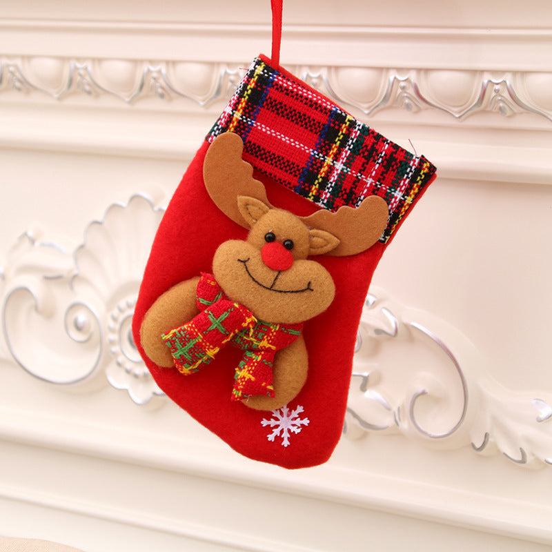 Red Christmas stocking with reindeer decoration and plaid cuff hanging on white mantle Christmas decorations
