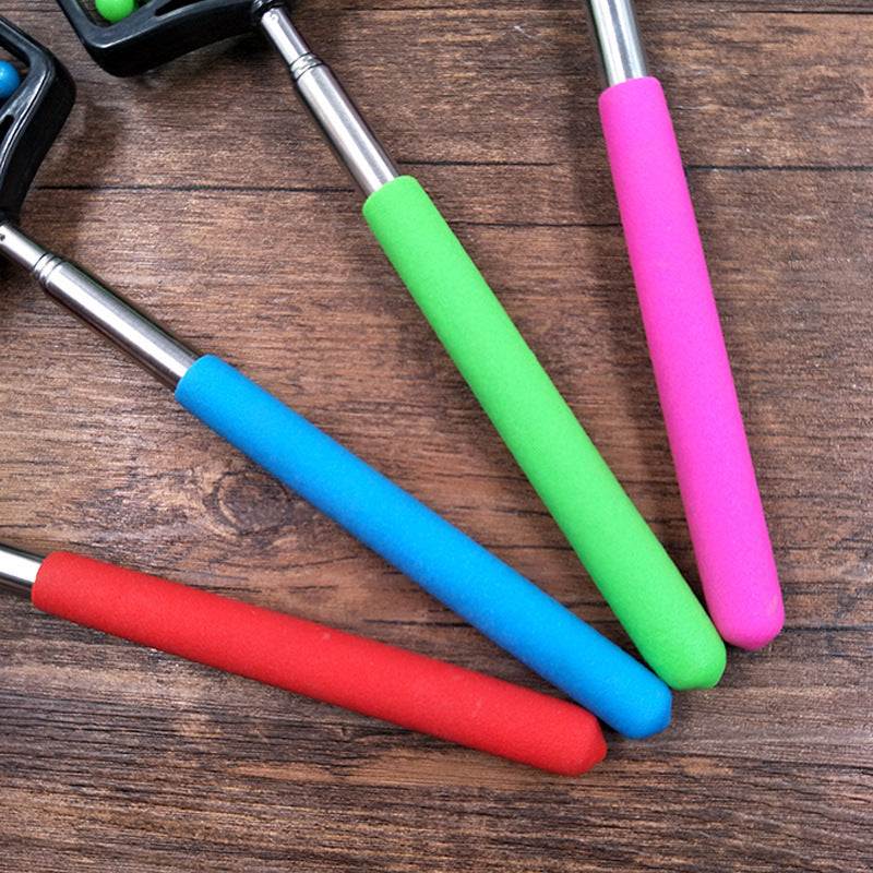 Telescopic plastic massage roller with colorful handles on wooden surface