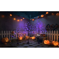 Three Halloween spooky trees with purple LED lights in a dark outdoor setting surrounded by jack-o'-lanterns and pumpkin decorations