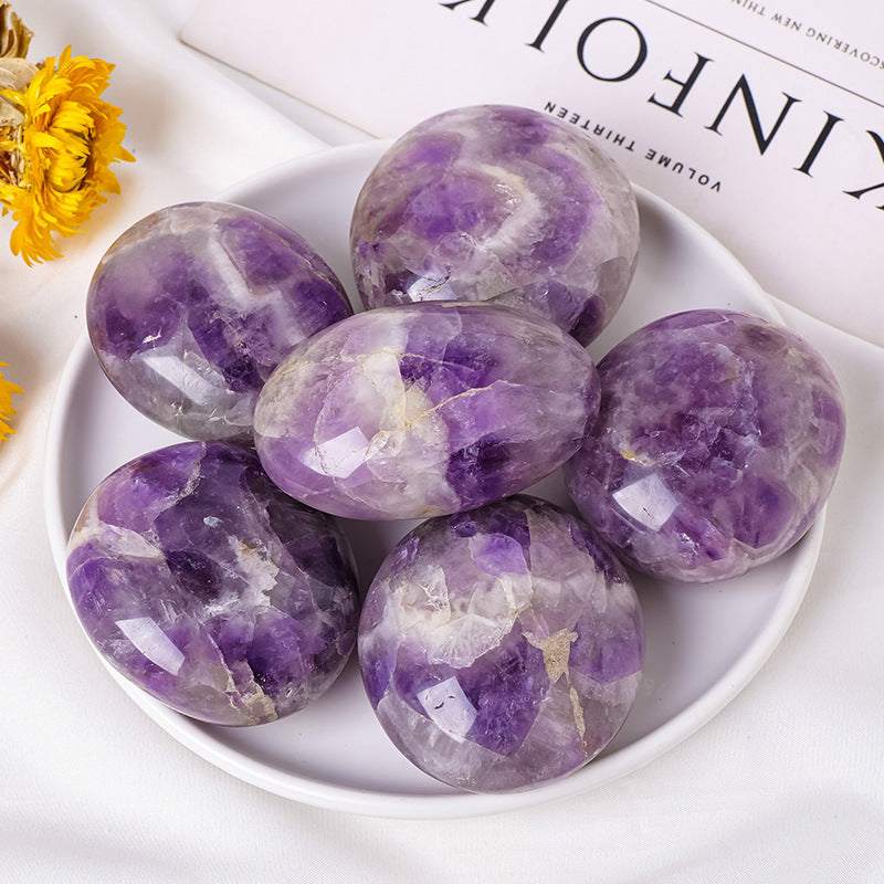 Natural crystal hot compress oval stones in purple and white on a plate for modern simplicity therapy