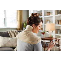 Woman using electric heating shoulder guard neck wrap for pain relief at home